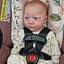 baby, infant, car_seat, safety_belt, blue_eyes, floral_pattern, onesie, cushion, pink_background, child, seat, clothing, straps, warning_label, portrait, cute, person, sitting, indoors, young