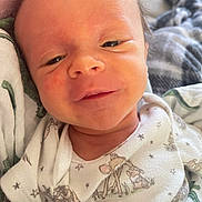Easton joined the competition — help win amazing prizes! newborn, baby, infant, child, portrait, face, sleepy, eyes, smiling, clothing, onesie, blanket, swaddle, stars, animals, indoors, close_up, head, cozy, photography