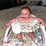 baby, infant, smiling, baby_seat, sock, striped_sock, blanket, carpet, toy, happy, child, indoor, floor, face, person, cute, comfort, seat, patterned_fabric, plush