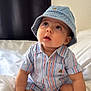baby, bed, child, clothing, curious, cute, denim, expression, feet, hands, hat, indoors, infant, looking_up, person, portrait, sitting, skin, striped_shirt, white_bed