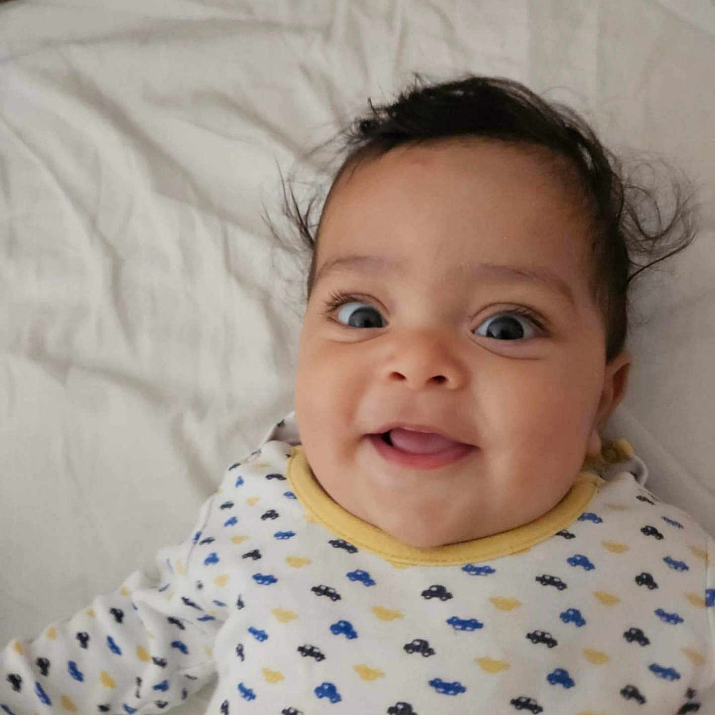 Zeyd participe au concours pour gagner de l'argent avec cette photo : adorable, baby, bed, child, closeup, cute, expression, face, happy, indoor, infant, joyful, lying_down, onesie, patterned_clothing, person, portrait, smiling, white_bedspread, young_child