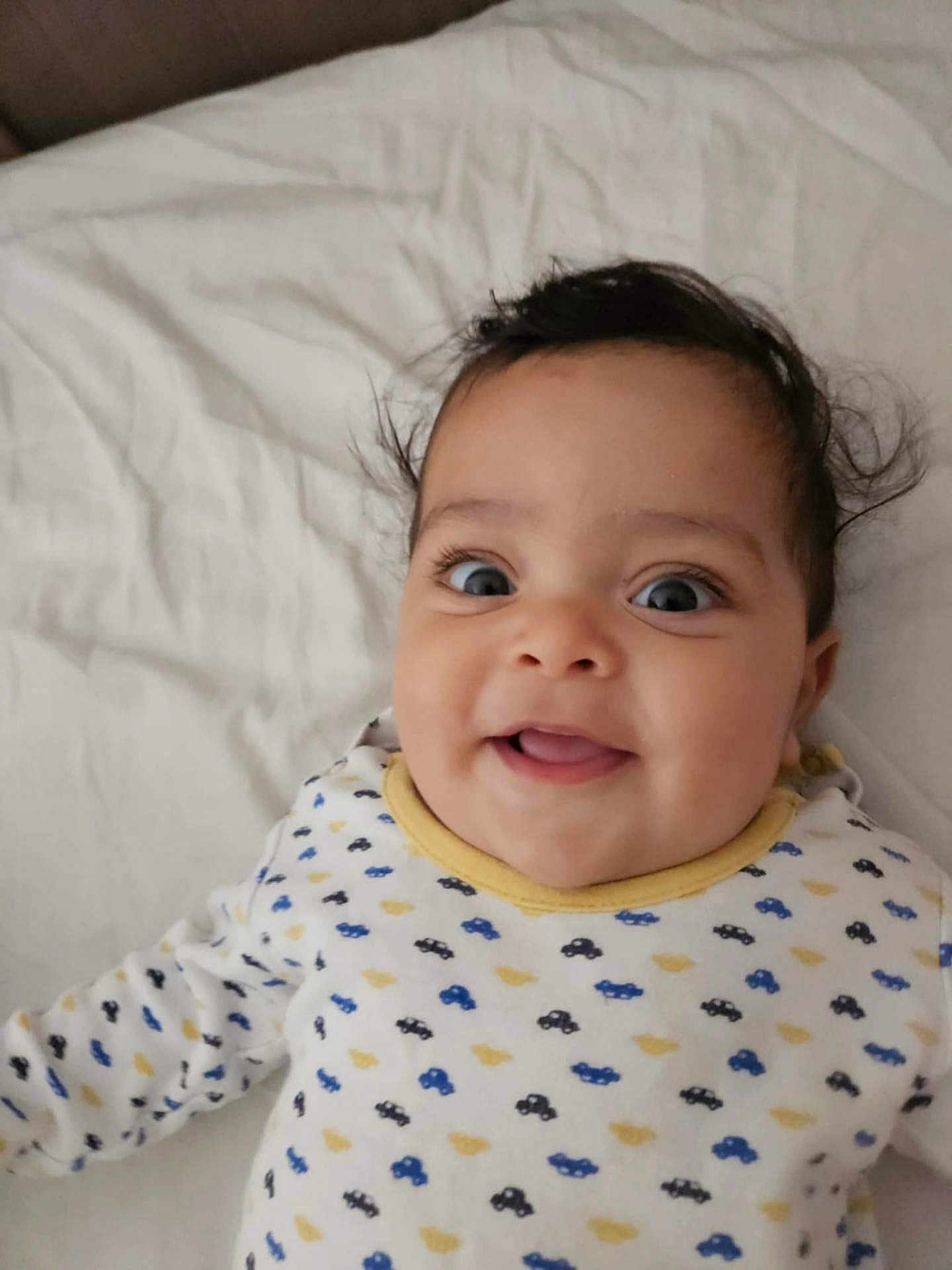 Zeyd participe au concours pour gagner de l'argent avec cette photo : baby, smiling, infant, face, cute, onesie, patterned_clothing, bed, white_bedspread, happy, child, lying_down, indoor, portrait, closeup, young_child, person, expression, joyful, adorable