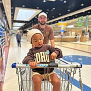 Soan a rejoint le concours — aidez-le/la à gagner de superbes lots ! adult, aisle, beige_shorts, cap, casual_clothing, child, floor, focus, glasses, grocery_store, hat, indoor, lighting, person, retail, shopping, shopping_cart, sneakers, supermarket, sweatshirt