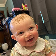 Elowyn Saige joined the competition — help win amazing prizes! baby, child, smile, happy, indoor, person, face, hair, curtain, furniture, dress, collar, pattern, skin, eyes, ear, room, light, toy, cute