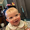 baby, child, smile, happy, indoor, person, face, hair, curtain, furniture, dress, collar, pattern, skin, eyes, ear, room, light, toy, cute