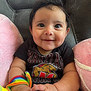 Aurora Perez joined the competition — help win amazing prizes! baby, black_shirt, bright_eyes, child, chubby_arms, closeup, colorful, cute, face, happy, indoor, infant, maryland, pink_cushions, portrait, rainbow_toy, sitting, smiling, soft, toy
