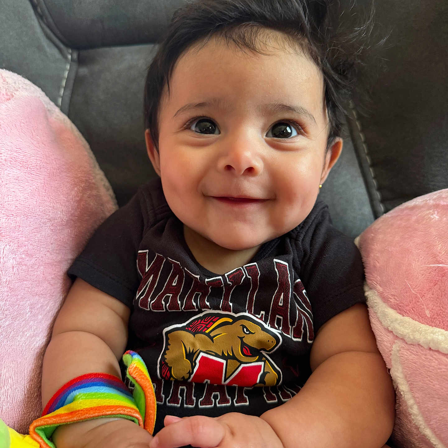 Aurora Perez joined the competition — help win amazing prizes! baby, black_shirt, bright_eyes, child, chubby_arms, closeup, colorful, cute, face, happy, indoor, infant, maryland, pink_cushions, portrait, rainbow_toy, sitting, smiling, soft, toy