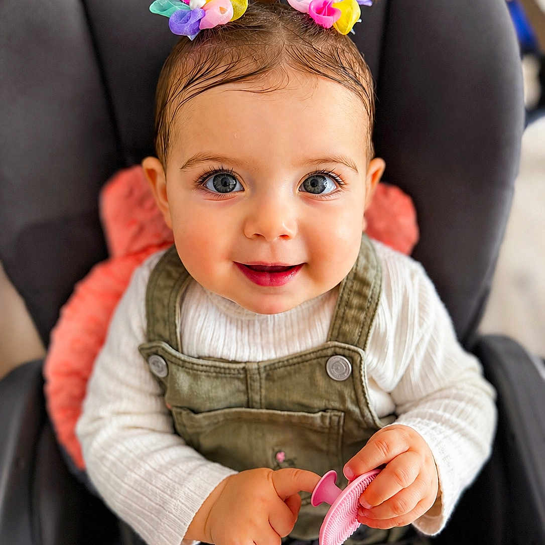 Giorgia participe au concours pour gagner de l'argent avec cette photo : baby, child, face, blue_eyes, hair_accessories, smiling, car_seat, toy, hands, clothing, overalls, white_sweater, cute, infant, portrait, indoor, happy, skin, expression, seatbelt