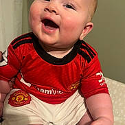 Wyatt joined the competition — help win amazing prizes! baby, child, smiling, happy, red_jersey, manchester_united, sportswear, shorts, barefoot, indoor, portrait, cute, cheerful, infant, sitting, head, face, person, skin, clothing