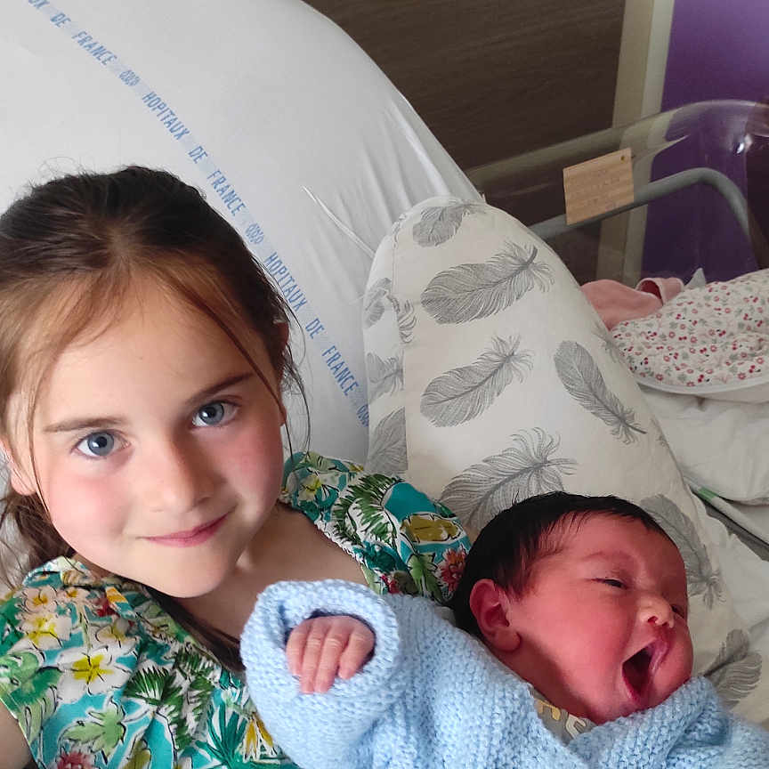 Ilyanah a rejoint le concours — aidez-le/la à gagner de superbes lots ! baby, bed, blanket, blue_sweater, caring, child, cute, face, family, holding, hospital, hospital_bed, indoor, newborn, person, pillow, portrait, smile, yawning, young_girl