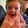 baby, child, closeup, expression, face, fireplace, furniture, hair, hand, human, indoor, infant, interaction, joy, laugh, living_room, person, skin, smile, stone_wall