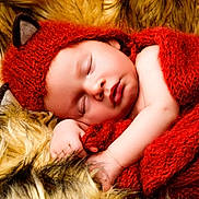 George is registered to the contest to win money with this photo: baby, sleeping, red_hat, knit_blanket, fur_blanket, infant, cute, cozy, soft_texture, newborn, peaceful, wrapped, face, hand, portrait, resting, warm_colors, adorable, child, sleep