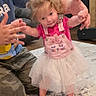 child, toddler, girl, standing, smiling, pink_dress, tutu, overalls, barefoot, indoor, home, living_room, carpet, door, adult, hands, family, portrait, playful, dance
