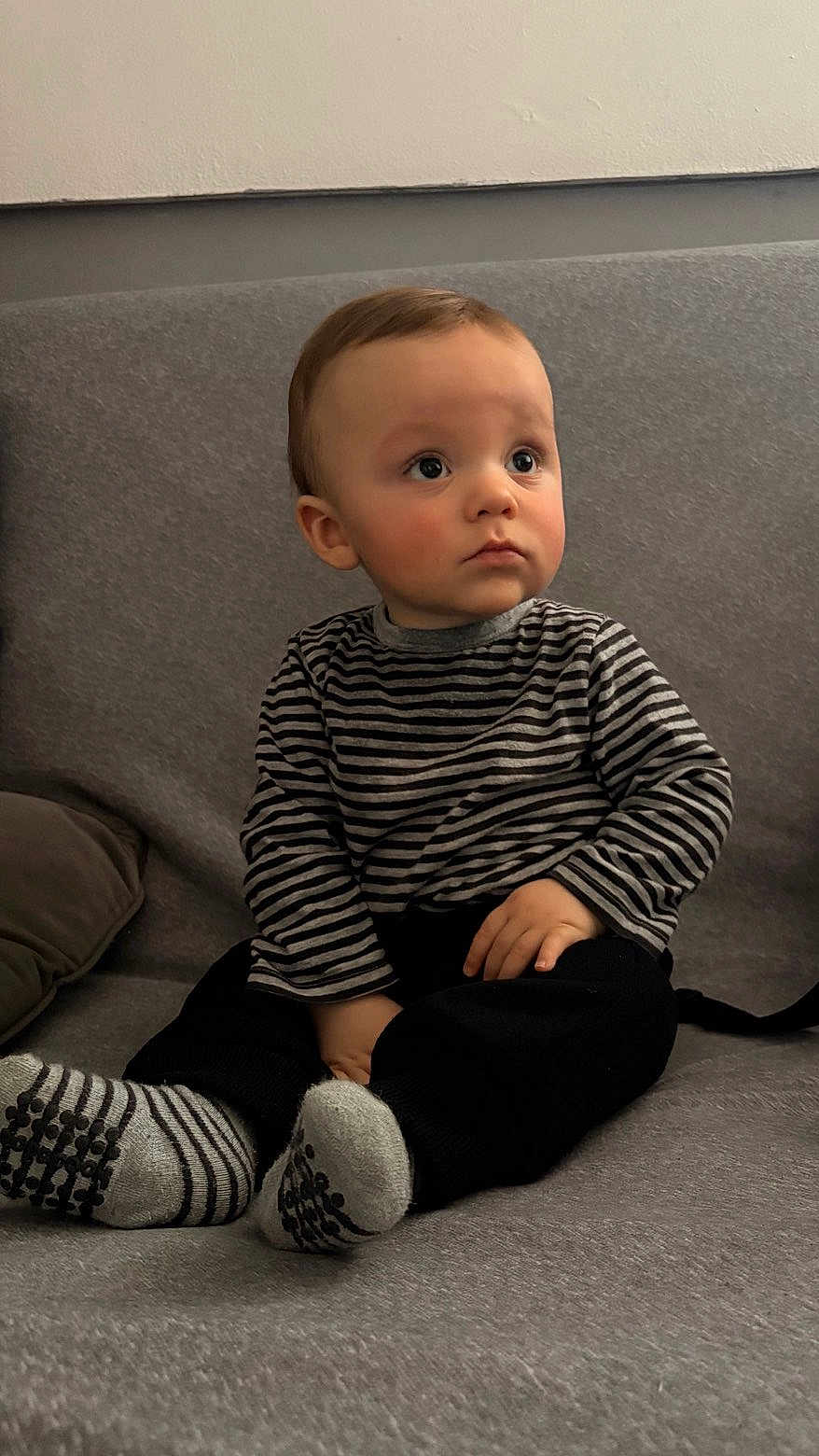 Kaylon a rejoint le concours — aidez-le/la à gagner de superbes lots ! toddler, child, striped_shirt, socks, couch, gray, indoors, sitting, portrait, cute, young_child, face, looking_away, clothing, hands, feet, cozy, casual, home, expression