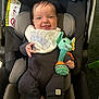 baby, car_seat, smiling, bib, plush_toy, elephant_toy, onesie, blanket, infant, child, happy, indoor, seatbelt, head_support, clothing, toy, person, portrait, cute, comfort