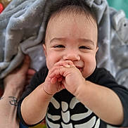 Lucian joined the competition — help win amazing prizes! arm, baby, background, black_clothing, blanket, child, closeup, cute, face, hands, happy, indoors, infant, person, playing, portrait, skeleton_outfit, smiling, tattoo, toddler