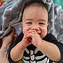 arm, baby, background, black_clothing, blanket, child, closeup, cute, face, hands, happy, indoors, infant, person, playing, portrait, skeleton_outfit, smiling, tattoo, toddler
