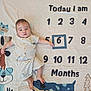Lucian joined the competition — help win amazing prizes! animal_illustrations, baby, baby_clothes, cartoon_characters, child, cute, fabric_background, indoors, infant, lying_down, milestone_blanket, milestone_photo, months, number_six, portrait, relaxed, smiling, soft_lighting, striped_outfit, young_child