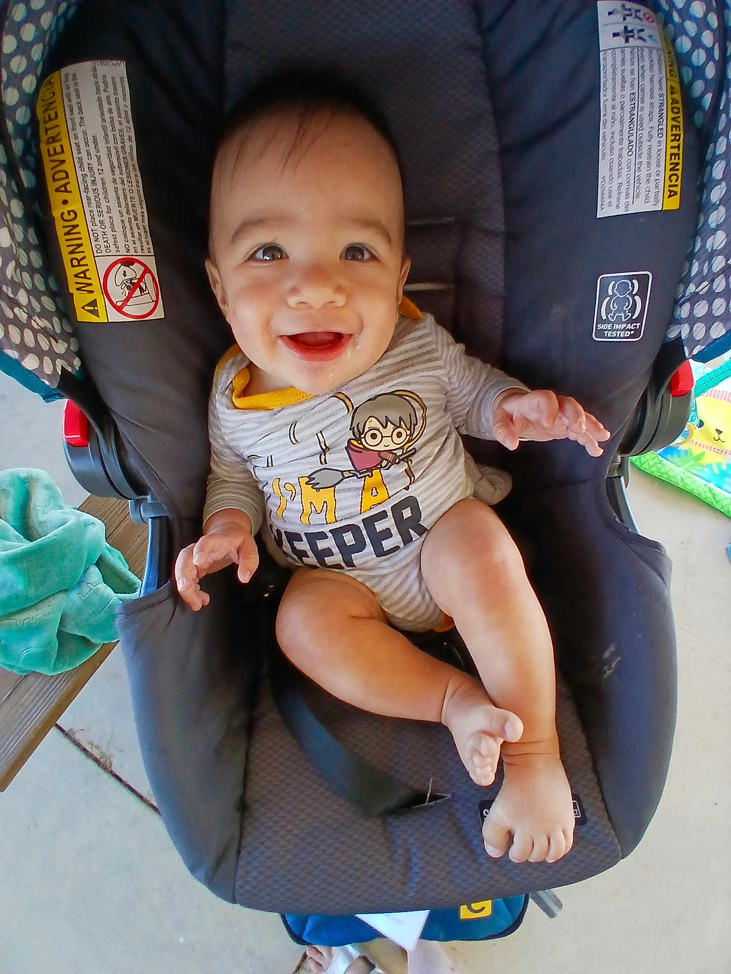 Lucian is registered to the contest to win money with this photo: baby, car_seat, casual, child, cute, expression, face, footwear, hands, happy, indoor, infant, legs, onesie, person, seat, smiling, striped_clothing, towel, toy