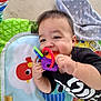 Lucian is registered to the contest to win money with this photo: baby, black_shirt, blanket, bright_colors, chewing, child, colorful, cute, face, floor, hand, happy, indoors, infant, pattern, playmat, playtime, skeleton_print, smiling, toy