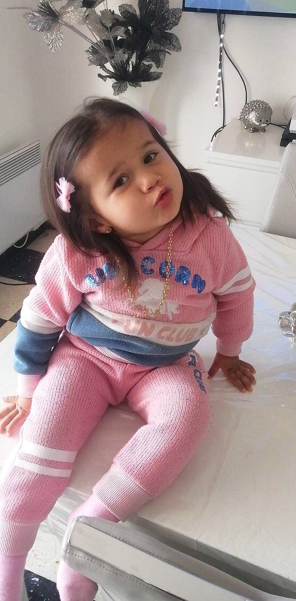 Mia a rejoint le concours — aidez-le/la à gagner de superbes lots ! arm, baby_toddler_clothing, black_hair, eye, face, finger, hair, head, human_body, joint, knee, mouth, neck, person, pink, shorts, skin, sleeve, smile, thigh