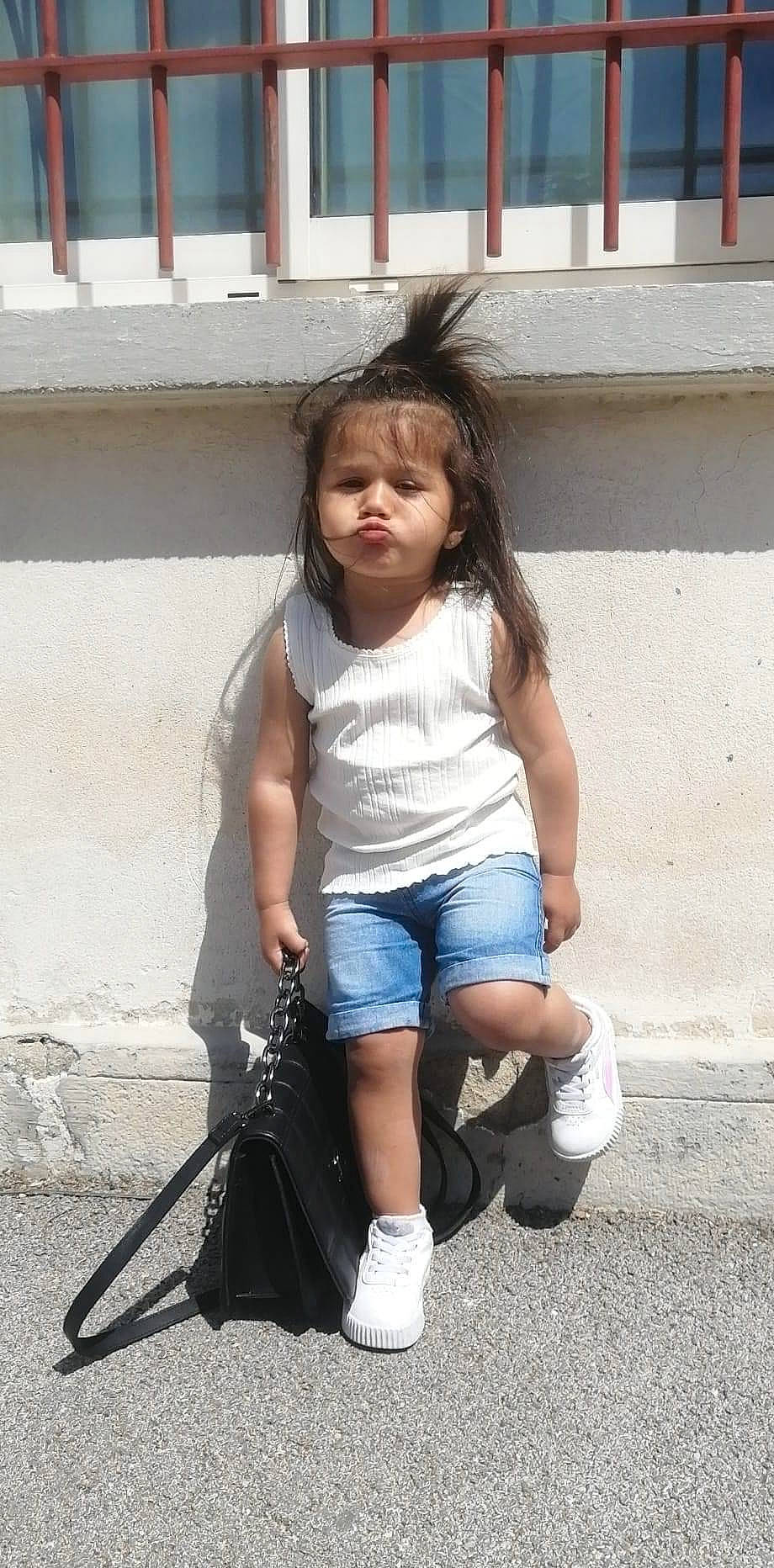 Mia a rejoint le concours — aidez-le/la à gagner de superbes lots ! asphalt, concrete, denim, elbow, electric_blue, footwear, happy, human_leg, knee, leg, person, recreation, sandal, shoe, shorts, sitting, sneakers, t_shirt, thigh, toddler