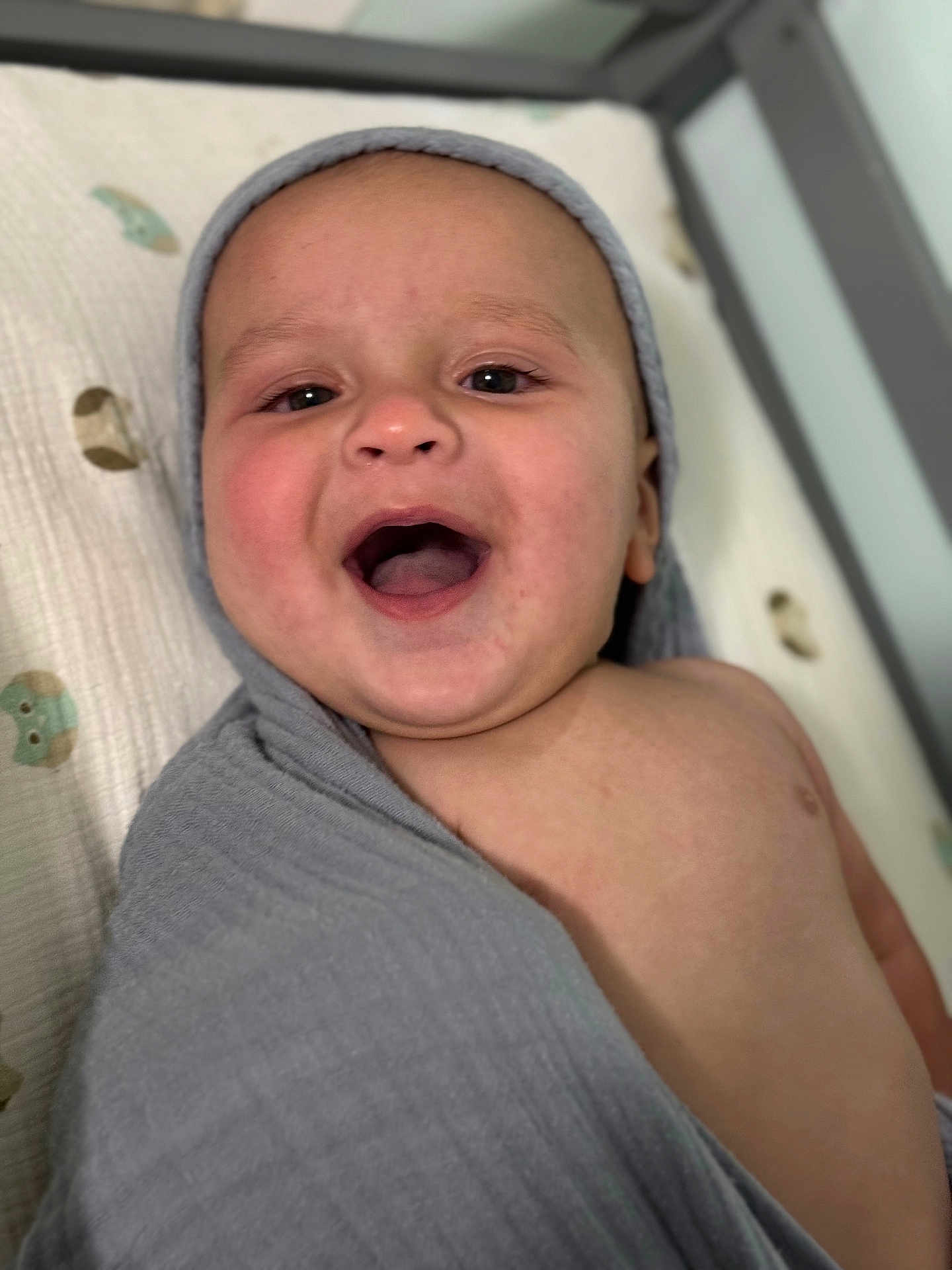 Silas joined the competition — help win amazing prizes! baby, infant, smiling, blanket, gray, happy, face, child, cute, portrait, expression, lying_down, skin, mouth_open, indoors, mattress, fabric, head, wrapped, person