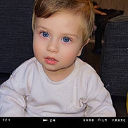 Dominik Doroftea is registered to the contest to win money with this photo: toddler, child, portrait, face, blue_eyes, blond_hair, white_shirt, sitting, indoors, couch, furniture, cozy, looking_at_camera, neutral_expression, close_up, photography, film_frame, home, baby, people