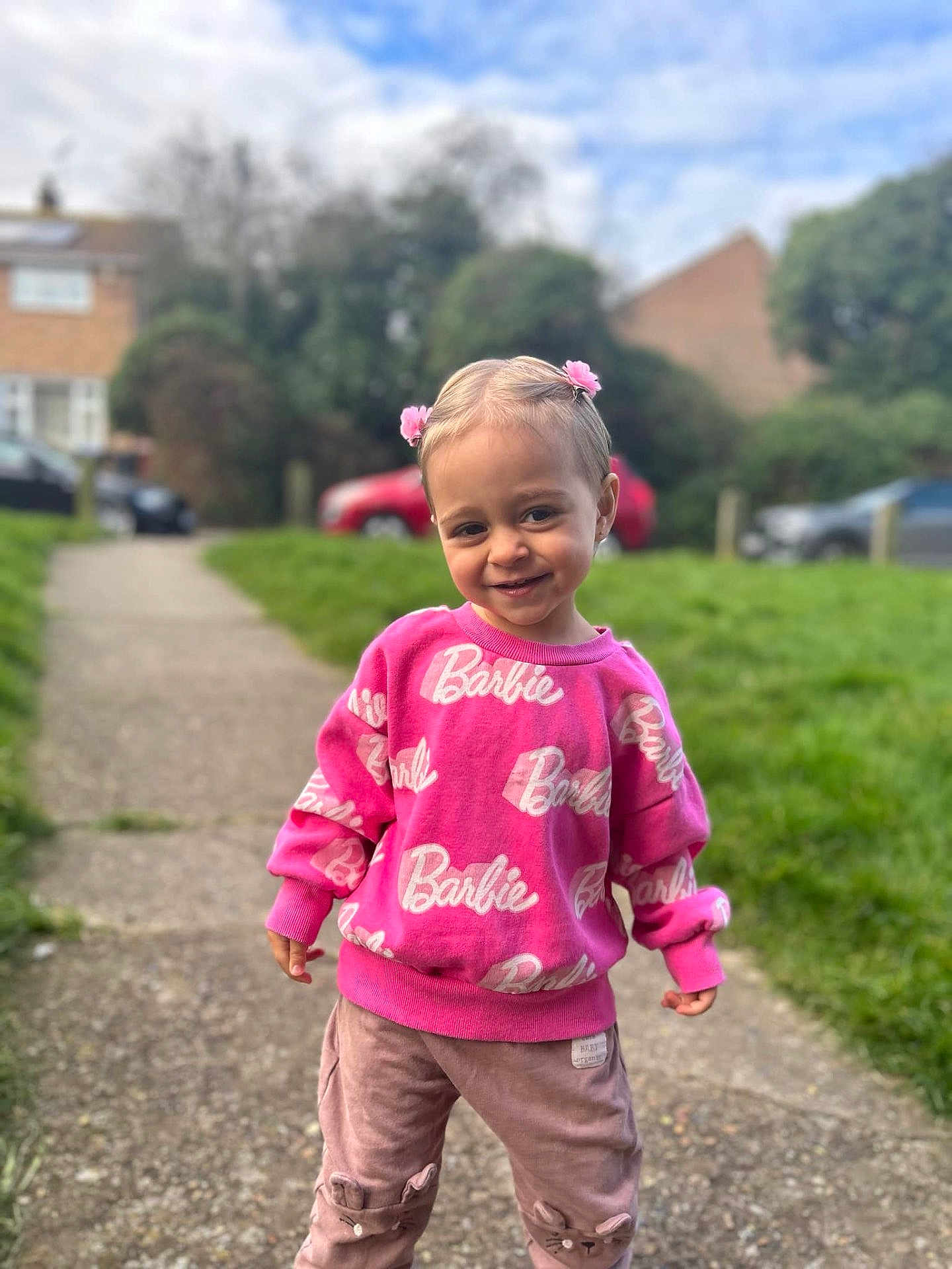 Olivia joined the competition — help win amazing prizes! child, toddler, smile, pink_sweater, barbie, hair_clips, outdoor, sidewalk, grass, pants, cute, happy, person, portrait, fashion, casual_wear, young_child, daylight, greenery, suburban