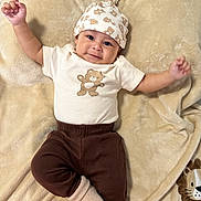 Eliano is registered to the contest to win money with this photo: baby, infant, smiling, face, hat, bear_print, brown_pants, sock, blanket, plush_toy, cute, cozy, lying_down, child, apparel, soft_texture, happy, portrait, one_person, indoors