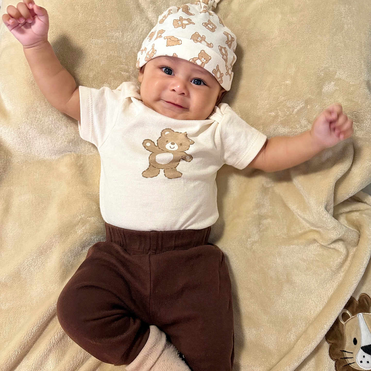 Eliano is registered to the contest to win money with this photo: apparel, baby, bear_print, blanket, brown_pants, child, cozy, cute, face, happy, hat, indoors, infant, lying_down, one_person, plush_toy, portrait, smiling, sock, soft_texture
