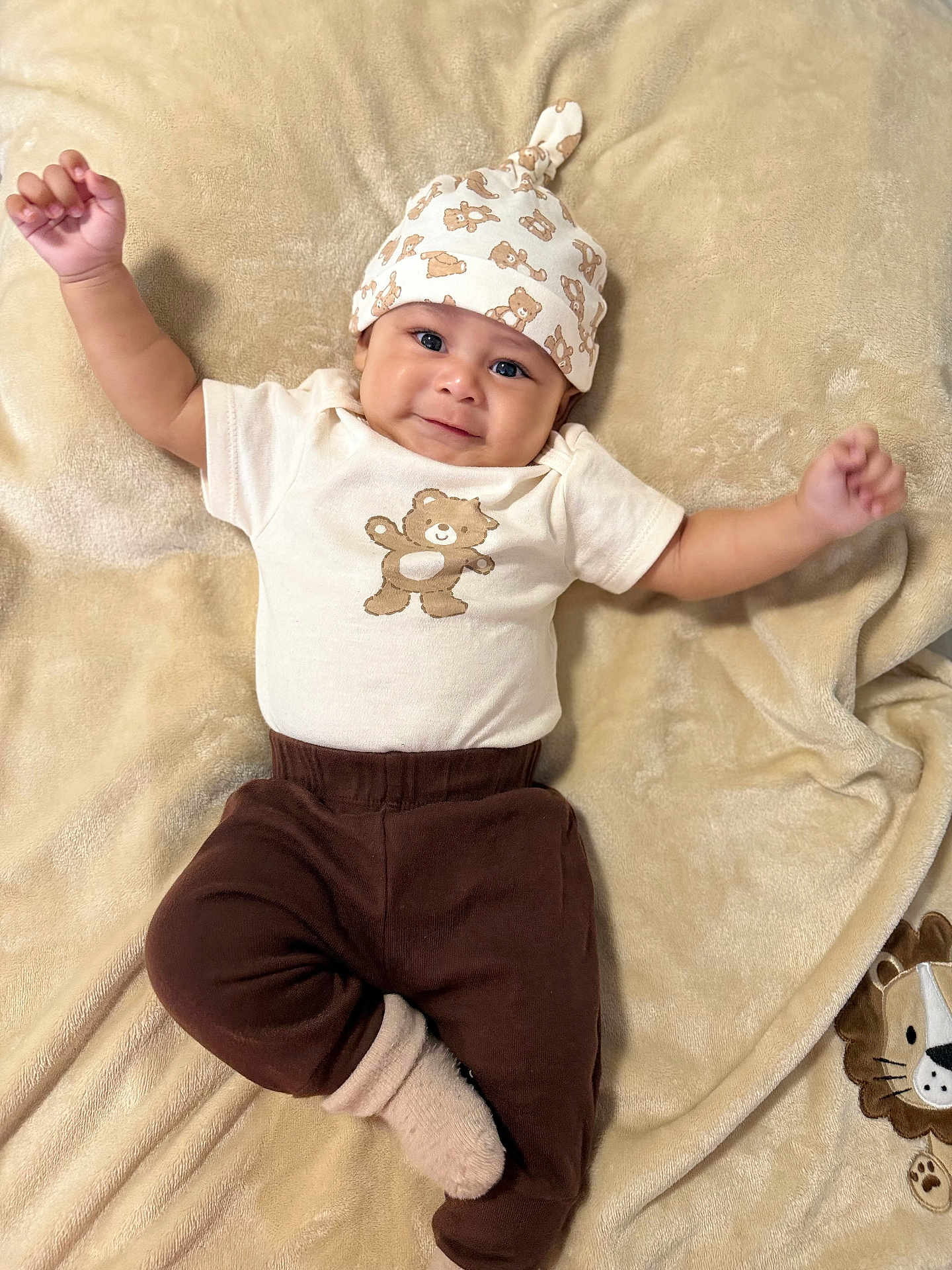 Eliano is registered to the contest to win money with this photo: baby, infant, smiling, face, hat, bear_print, brown_pants, sock, blanket, plush_toy, cute, cozy, lying_down, child, apparel, soft_texture, happy, portrait, one_person, indoors