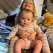 Rosey is registered to the contest to win money with this photo: baby, child, sibling, smiling, bed, blanket, pajamas, indoor, cute, family, person, happy, toddler, holding, furniture, plush, footwear, head, face, home