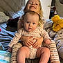 baby, child, sibling, smiling, bed, blanket, pajamas, indoor, cute, family, person, happy, toddler, holding, furniture, plush, footwear, head, face, home