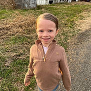 Lily is registered to the contest to win money with this photo: child, smiling, outdoor, grass, mobile_home, shed, graffiti, jacket, jeans, sneakers, portrait, happy, face, neat_hair, earring, gravel_path, dry_grass, sunlight, casual_clothing, rural