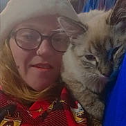 Precious is registered to the contest to win money with this photo: person, cat, indoors, santa_hat, glasses, sweater, sponge_bob, cozy, couch, relaxed, pet, feline, portrait, closeup, home, holiday, smiling, casual, red, blue