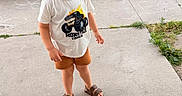 Shane joined the competition — help win amazing prizes! child, boy, smiling, outdoor, sidewalk, concrete, tshirt, monster_truck, shorts, sandals, grass, plants, wooden_beds, garden, greenery, happy, standing, casual_clothing, daylight, portrait