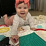 baby, smiling, headband, bow, play_mat, mirror, reflection, indoor, child, curious, hand, face, clothing, long_sleeve, floor, toy, colorful, happy, infant, portrait