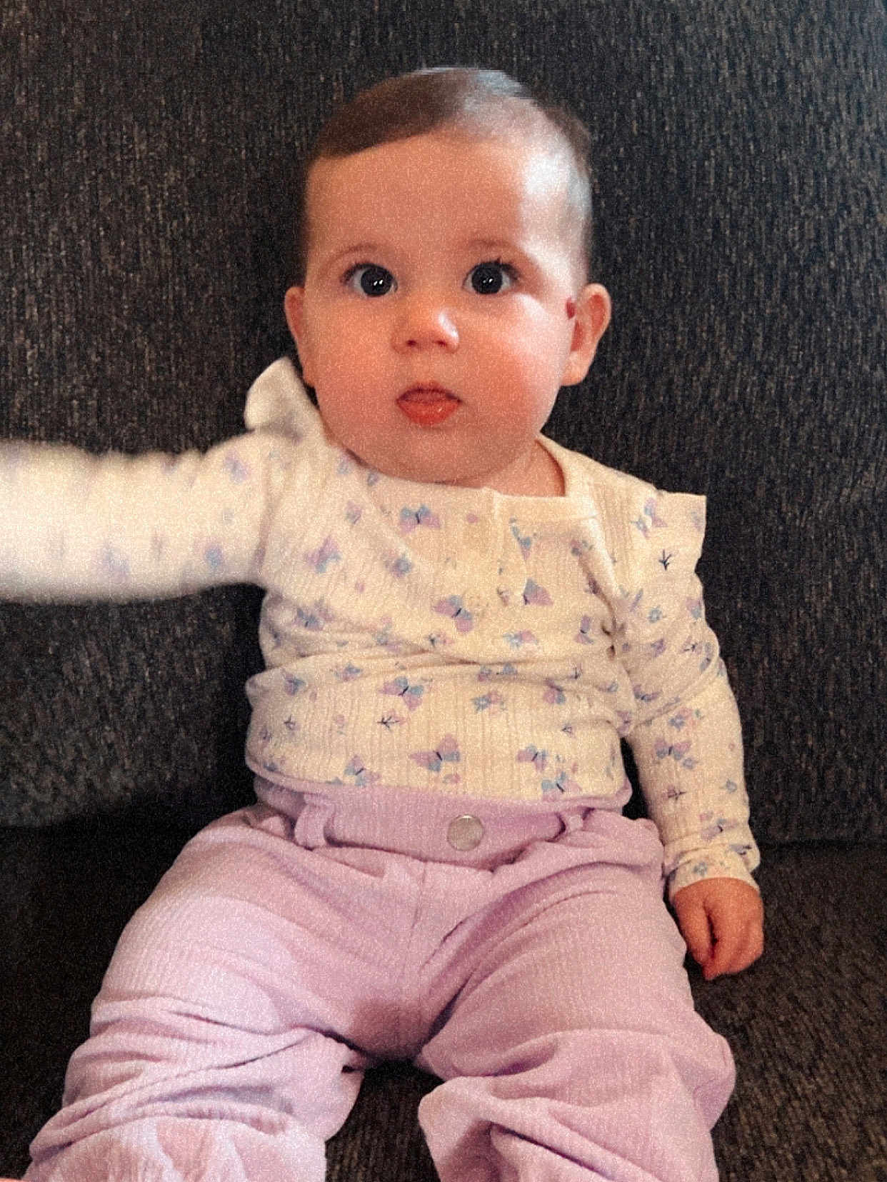 Oaklee is registered to the contest to win money with this photo: baby, child, infant, sitting, couch, clothing, pastel_colors, long_sleeve, pants, curious, face, tongue_out, indoors, young_child, portrait, seated, texture, expression, small_hand, cute