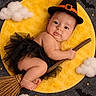 baby, child, witch, halloween, costume, hat, broomstick, moon, clouds, bats, stars, infant, portrait, lying_down, cute, black_tutu, orange, fantasy, studio_photo, smiling