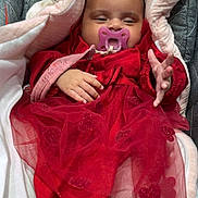 Aliyah participe au concours pour gagner de l'argent avec cette photo : baby, infant, pacifier, red_dress, blanket, cozy, child, cute, hand, clothing, portrait, indoors, warm, soft, smiling, toddler, wrapped, nap, resting, car_seat