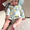 Gianna joined the competition — help win amazing prizes! baby, infant, smile, hat, lemon_pattern, outfit, couch, furniture, hand, foot, face, eyes, skin, indoor, child, clothing, cute, relaxed, portrait, seated