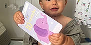 Soul-Atlas is registered to the contest to win money with this photo: baby, baby_clothes, child, clothing, cute, decor, elephant, face, happy, holding, indoor, infant, milestone_card, patterned_surface, portrait, room, sitting, smiling, soft_lighting, young_child
