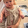 toddler, child, adult, indoor, carpet, romper, holding, furniture, toy, person, seated, curious, face, hand, footwear, room, blanket, couch, decor, play
