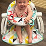 baby, smiling, baby_walker, pink_clothing, cherries, toys, floor, wooden_floor, colorful, happy, child, indoor, footwear_none, person, infant, seat, playful, cute, face, home