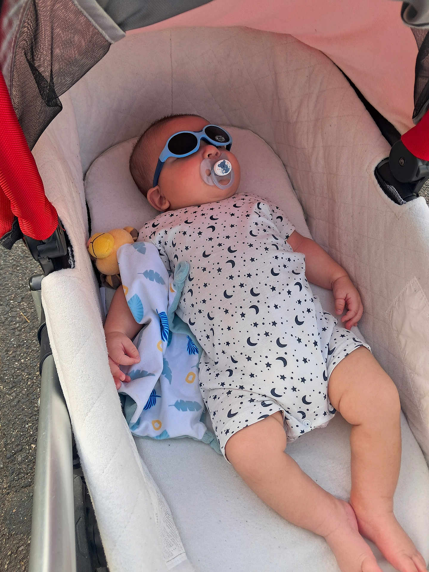 Massyl participe au concours pour gagner de l'argent avec cette photo : baby, child, stroller, sunglasses, pacifier, toy, blanket, onesie, patterned_clothing, infant, relaxing, outdoor, shade, cute, sleeping, hand, foot, face, head, comfort