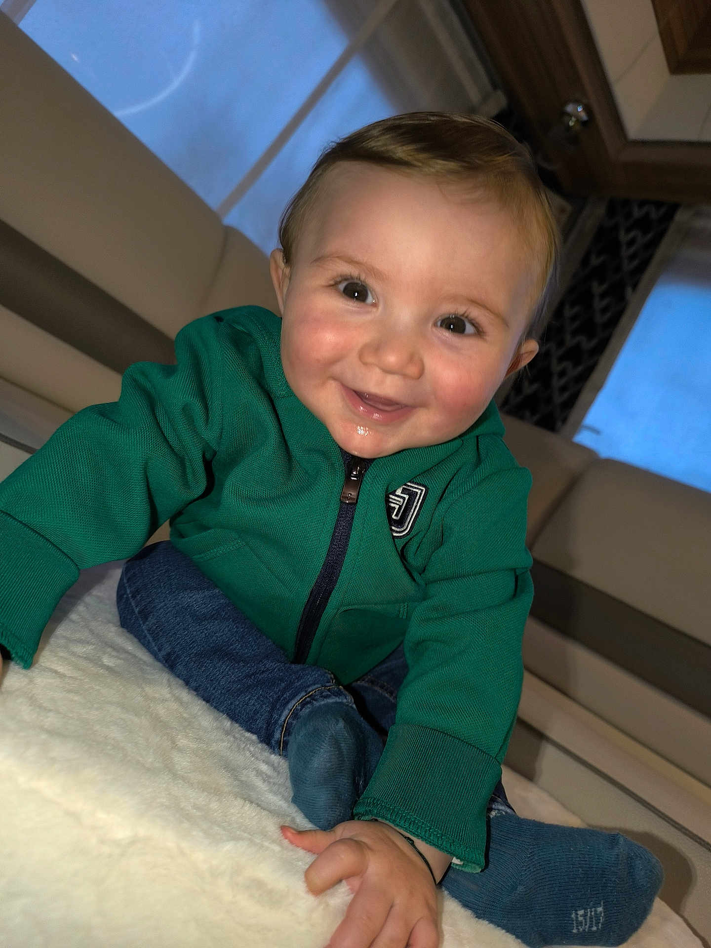Jacques participe au concours pour gagner de l'argent avec cette photo : baby, child, smiling, green_jacket, blue_socks, crawling, indoor, blanket, happy, cute, face, portrait, person, clothing, young_child, home, cozy, infant, jeans, sitting