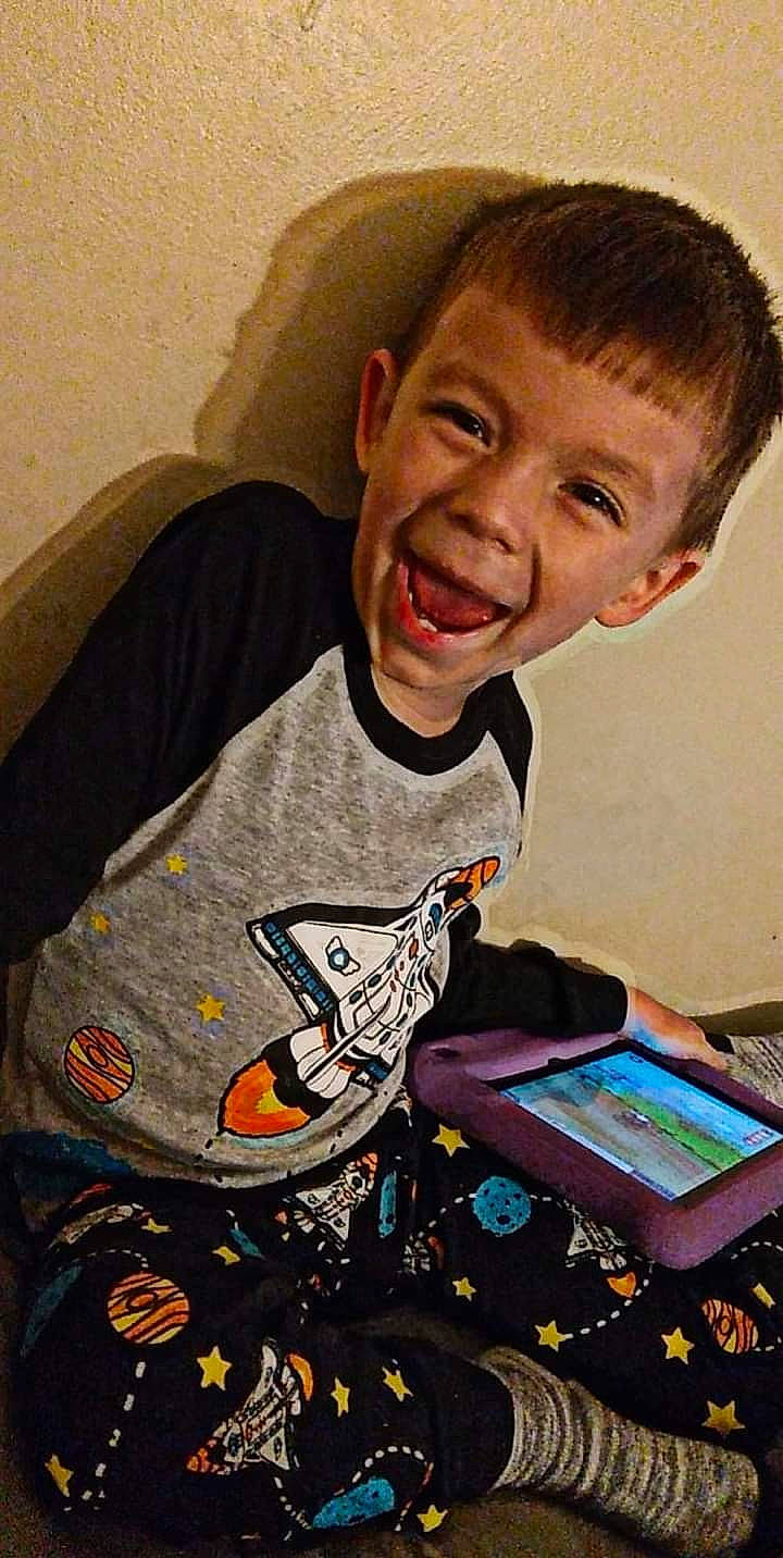 Alonzo is registered to the contest to win money with this photo: carmine, child, electronic_device, forehead, fun, gadget, games, happy, head, indoor_games_and_sports, person, play, recreation, room, sitting, sleeve, smile, t_shirt, tablet_computer, toddler