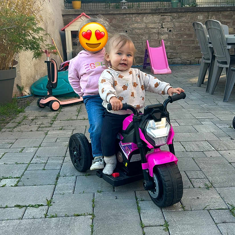 Marha a rejoint le concours — aidez-le/la à gagner de superbes lots ! backyard, casual_clothing, chair, child, daylight, fence, fun, outdoor, paved_ground, person, plant, play, potted_plant, scooter, slide, smiling, socks, stone_wall, table, toy_motorcycle