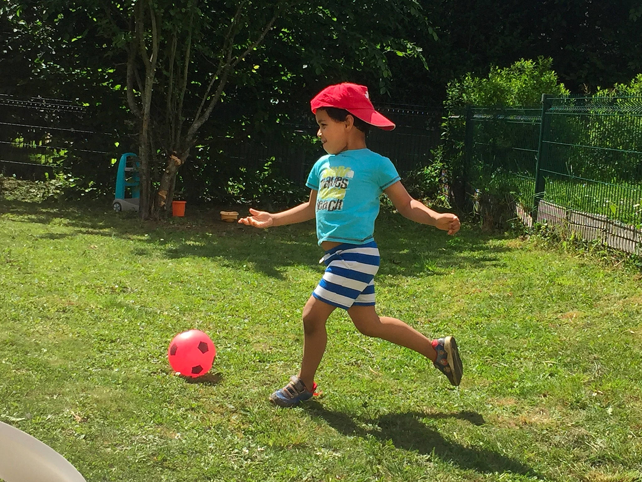 Maido participe au concours pour gagner de l'argent avec cette photo : ball, baseball_cap, fence, football, fun, grass, lawn, leisure, people_in_nature, person, plant, player, playing_sports, recreation, shorts, soccer, sports, sports_equipment, t_shirt, toddler